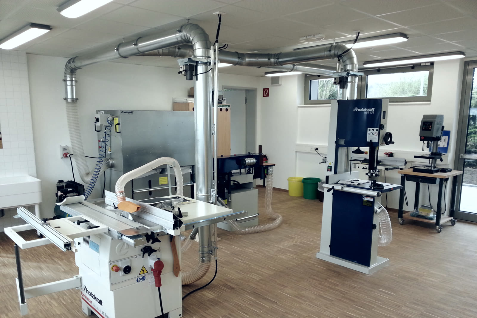 Werkraum einer Schule mit Formatkreissäge, Bandsäge, Dickenhobel, Ständerbohrmaschine und aufgebauter Absauganlage