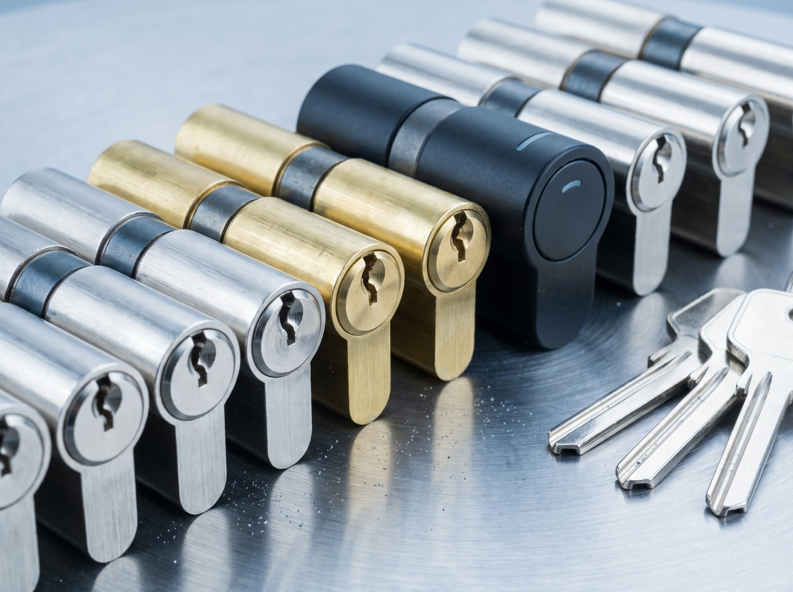 Profilzylinder in Nickel und Messing neben einem elektronischen Zylinder und mehreren Schlüsseln