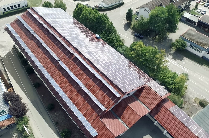 Luftbild des Betriebsgebäudes mit voll belegter Photovoltaikanlage auf dem Satteldach